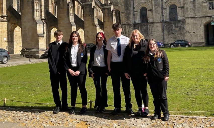 Year 10 pupils in school uniform standing outside Winchester Cathedral on a sunny day during their Religious Studies trip.
